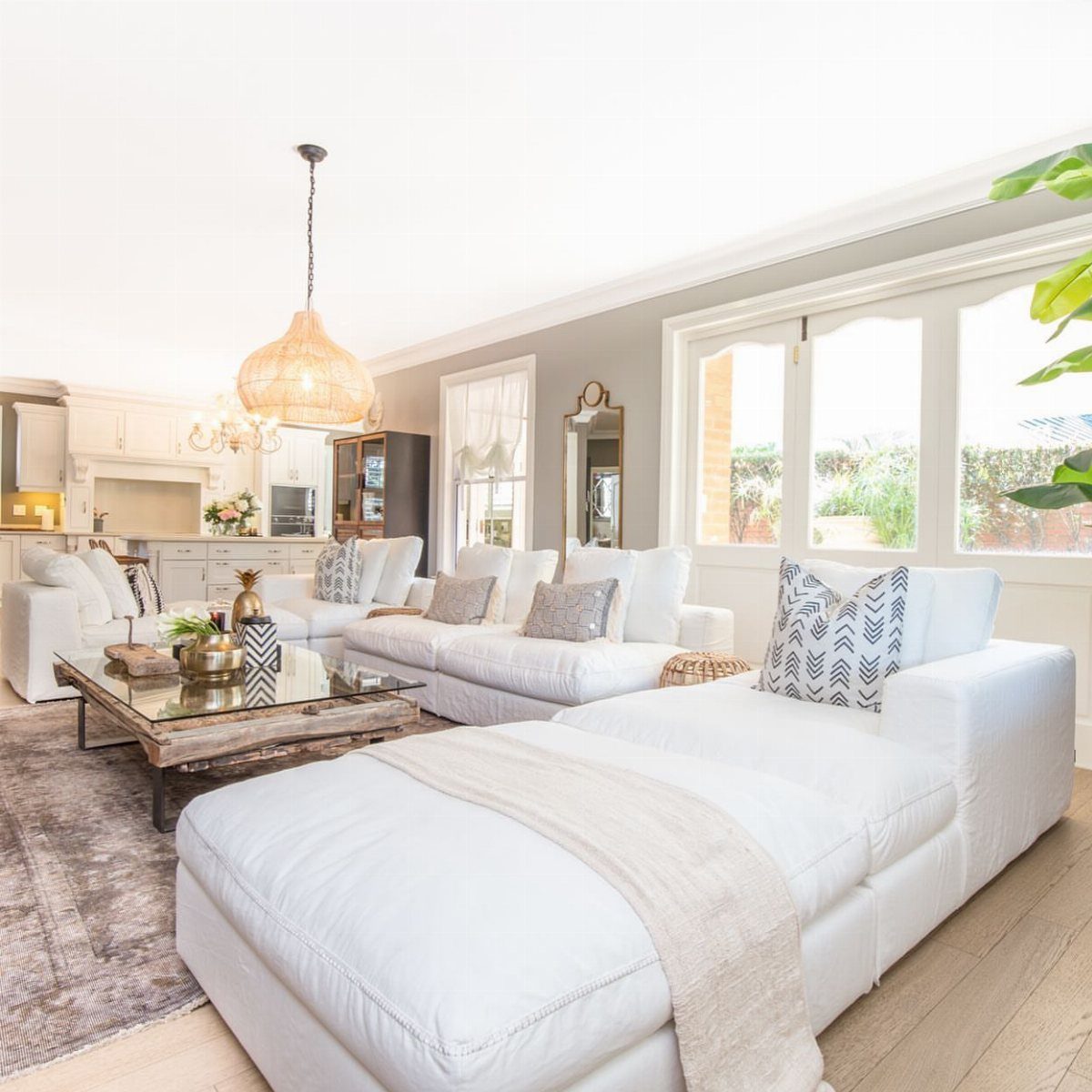 Large white sectional sofa in a bright living room with rustic wooden coffee table