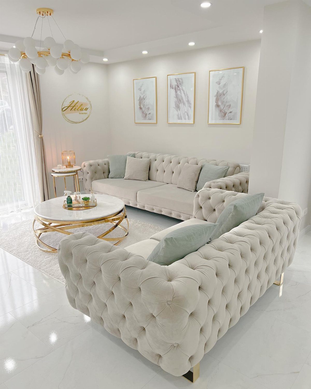 Two tufted white sofas with light blue pillows in a luxurious white living room.