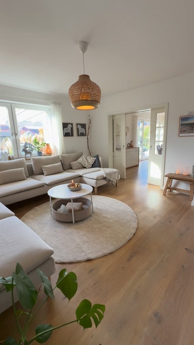 Light-colored sectional sofa in a bright living room with wooden floors and woven lamp.